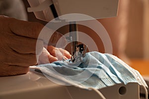 Hands of an elderly woman sew medical masks during the global pandemic in Ukraine