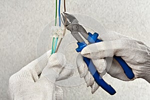 Hands of electrician cutting wires with clippers