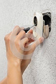 Hands of electrician dismantling broken old electric socket