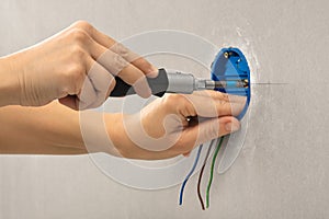Hands of electrician installing outlet box