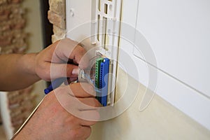 Hands of electrician installs electrical socket in photo