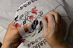 Hands of the embroiderer. Female hands with a needle, thread and thimble. Woman embroiders clothes. Traditional embroidery