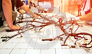 Hands of employees who check the quality of the wiring for cars at a modern plant on a special stand at the production shop