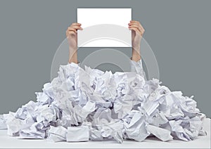 Hands with empty paper reaches out from big heap of crumpled papers
