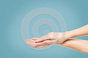 Hands. Empty two hands raised up, beg. Close up of beautiful female hands isolated on blue background