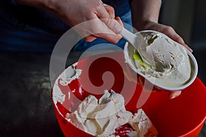 hands emptying the fresh white cheese from the packaging to mix it and prepare a cheesecake