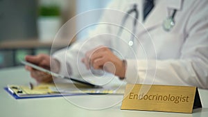 Hands of endocrinologist scrolling on tablet, modern technology, online service