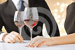 Hands of engaged couple with red wine in glasses