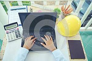 Hands of Engineer using laptop wear yellow helmet for safety. Construction Concept