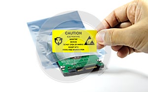 Hands of the engineers who are labeling the ESD protection label on the bag,The yellow CAUTION label for Electrostatic Sensitive