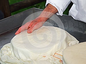 hands of expert cheesemaker over the freshly cheese in the dairy