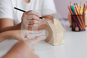 Hands of family father mother and daughther pointing to wooden house model metaphor dream for home building and decoration or