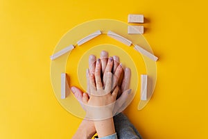 Hands of a father, mother and child one on top of the other placed in a house shape made of wooden pegs