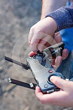 Hands of Father and son holding remote control joystick and piloting quadrocopter