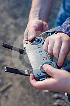 Hands of Father and son holding remote control joystick and piloting quadrocopter