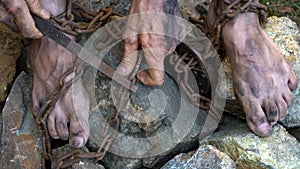 Hands and feet of a slave entangled in iron chains. An attempt to break free from slavery. The symbol of slave labor. Hands in