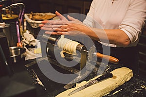 The hands of a female baker cook trdelnik or Trdlo national treat in the Czech Republic in winter