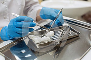 Hands female dentist holding dental tools over medical office background.