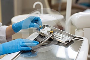 Hands female dentist holding dental tools and teeth over medical office background.