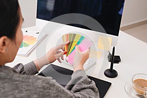 Hands of female designer in office working with colour samples. Woman at workplace choosing colourful paper charts. Creative
