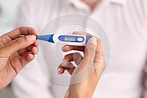 Hands of a female doctor holding a thermometer