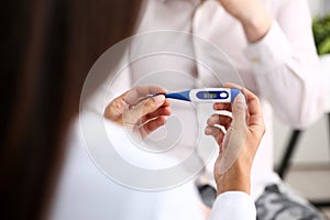 Hands of a female doctor holding a thermometer