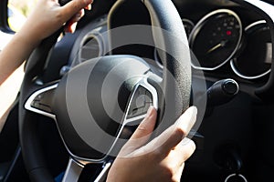 Hands of female driver on steering wheel.