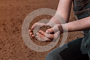 Hands of female farmer full of freshly ploughed fertile soil ground in springtime