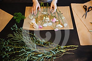 Hands of female florist making bouquet on black table