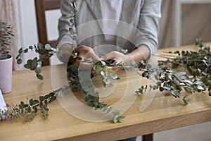 Hands of female flower arranger creating composition of fresh plants