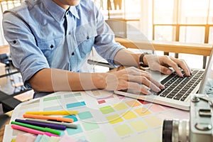 Hands of female hipster modern graphic designer in office working with colour samples. Woman at workplace choosing colourful swat