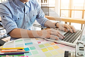 Hands of female hipster modern graphic designer in office working with colour samples. Woman at workplace choosing colourful swat