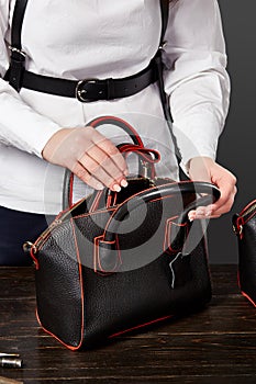 Female master checking completeness of black leather bag photo