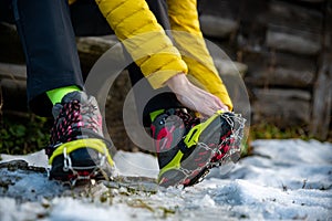 Hands female mountaineers wear crampons for boots before climbing the mountains in winter.