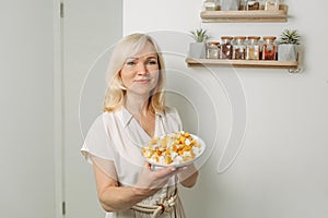 In the hands of a female nutritionist is a plate with a ready-made dish of zucchini and feta cheese