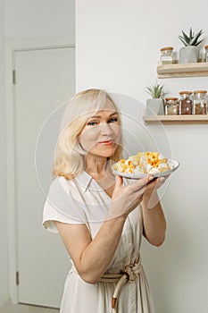 In the hands of a female nutritionist is a plate with a ready-made dish of zucchini and feta cheese