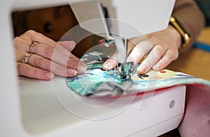 Hands of a female seamstress while working on a sewing machine