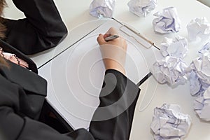 Hands of female writing with crumple paper at the desk