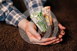 Hands with fertile soil and euro money banknotes