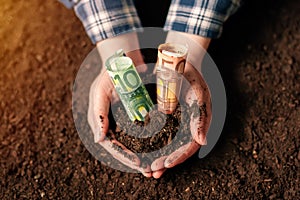 Hands with fertile soil and euro money banknotes