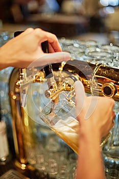 Hands fill mug with beer from beer