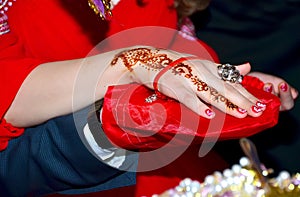 Hands and fingers are drawn to henna . Female hand with henna tattoo . Soft selective focus, close up . There are red lacquer and