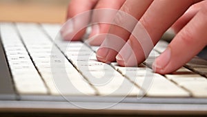 Hands, fingers fast typing on a white laptop keyboard, side view, computer keys extreme closeup, shallow dof. Man working on a