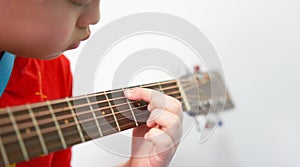 Hands and fingers grasping chords, playing the guitar. The boy looked down intently at the hand playing the guitar strings