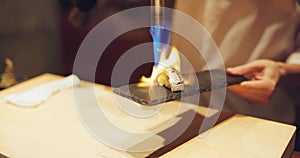 Hands, fire and cooking sushi with chef in restaurant for traditional Japanese food or cuisine closeup. Kitchen, flame