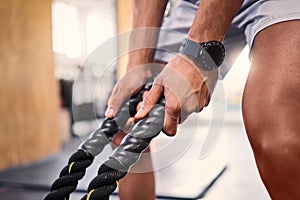 Hands, fitness and battle rope with a sports man training for cardio or endurance in a gym workout. Grip, heavy ropes