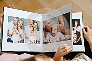 hands flip through the pages of a photo book with family photos.