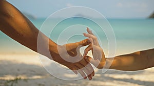 Hands of flirting young man and woman touching on sea beach