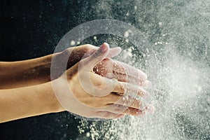 Hands with flour on a dark background
