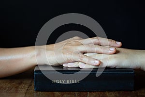 Hands folded in prayer on a Holy Bible